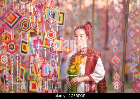 Porträt einer lächelnden Frau in traditioneller thailändischer Kleidung mit Blumen, Thailand Stockfoto