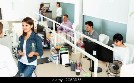 Mitarbeiter im Büro, die sich am Schreibtisch unterhalten Stockfoto