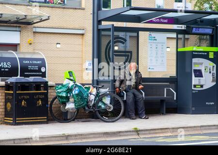 4. Juli 2021 EIN obdachloser älterer Herr mit seinem Fahrrad, das neben ihm steht, nimmt seinen gewohnten Platz für die Nacht in einem Translink Bus Shelter auf der Lo ein Stockfoto