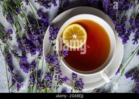 Tasse Tee mit einer Scheibe Zitrone, Lavendelblüten und einem Guten Morgen Tag auf einem Tisch Stockfoto