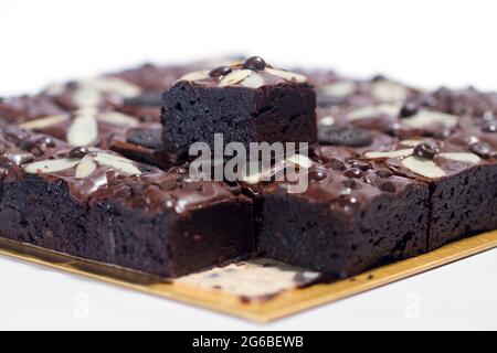 Quadrate von Schokoladenbrownies mit Mandeln auf einer Servierplatte Stockfoto