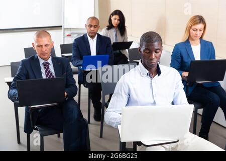 Gruppe von Personen, die während der Geschäftsschulung mit Laptops arbeiten Stockfoto