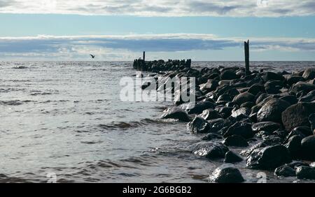 Ein alter Steinsteg ins Meer an einem sonnigen Abend. Dramatischer Look Stockfoto