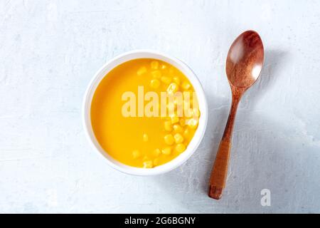 Maissuppe, von oben mit einem Holzlöffel geschossen. Einfaches veganes Brührezept Stockfoto