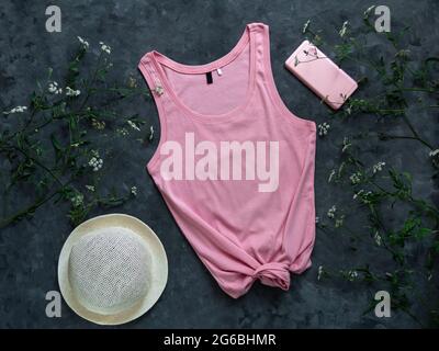 Tanktop aus rosa Baumwolle auf dunklem Hintergrund. Leere einfarbige T-Shirt-Vorlage für kreatives Design. Weibliche Sommer Sonnenbrillen Kleidung Mode ärmellos Stockfoto