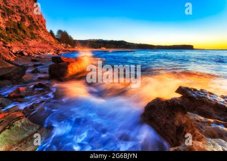 Farbenfrohe Wellen auf den Felsen von Newport Beach und Sydney Northern Beaches bei Sonnenaufgang. Stockfoto