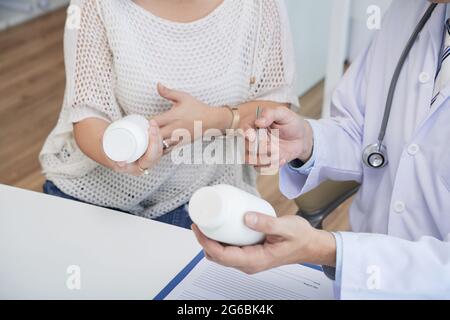 Hände eines Arztes, der Tabletten und Pillen für weibliche Patienten verschreibt Stockfoto