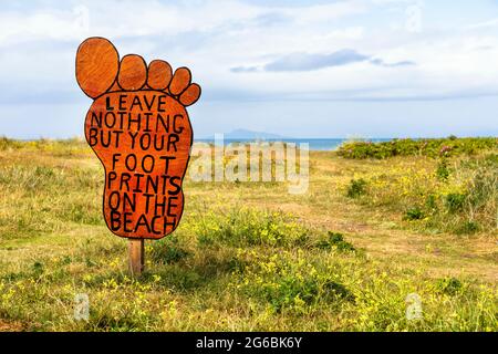 Anti-Verschmutzung-Schild in Form eines Fußes, auf dem Zufahrtsweg zum öffentlichen Strand von Troon, Ayrshire, Schottland, Großbritannien Stockfoto