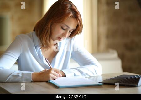 Konzentrierter Unternehmer, der den Vertrag unterzeichnet, sitzt zu Hause Stockfoto