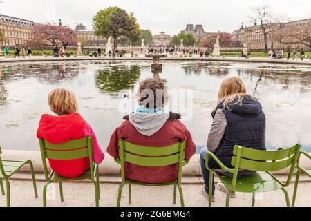 Drei Personen saßen vor einem Teich in den Tuilerien in Paris Stockfoto