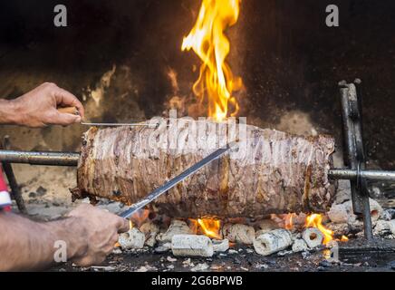 Nahaufnahme eines Mannes, der einen leckeren Döner-Kebab schneidet Stockfoto