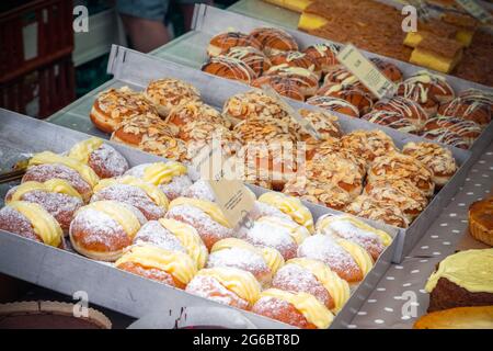 Eine Auswahl an berlinern, deutschen Donuts, wird auf dem Broadway Market, einem Straßenmarkt in Hackney, East London, ausgestellt Stockfoto