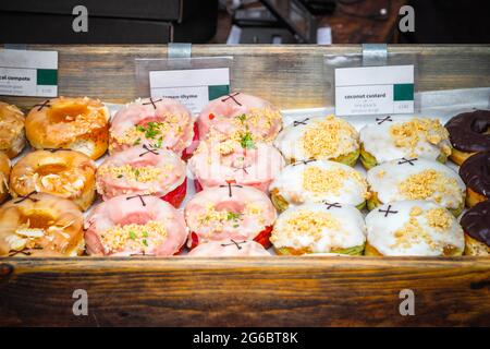 Eine Auswahl an Donuts, die auf dem Broadway Market, einem Straßenmarkt in Hackney, East London, ausgestellt werden Stockfoto