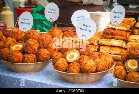 Auf dem Broadway Market, einem Straßenmarkt in Hackney, East London, werden verschiedene Scotch-Eier und andere herzhafte Gebäcksnacks ausgestellt Stockfoto