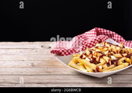 Traditionelles kanadisches Poutine auf Holztischdecke Stockfoto