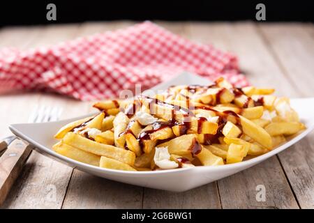 Traditionelles kanadisches Poutine auf Holztischdecke Stockfoto