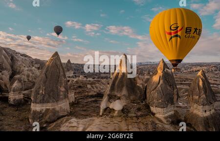 Göreme, Türkei - 19. März 2021 - herrlicher Panoramablick auf Landschaften mit Heißluftballonfahrten, die in Kappadokien, Türkei, bei Sonnenaufgang fliegen Stockfoto