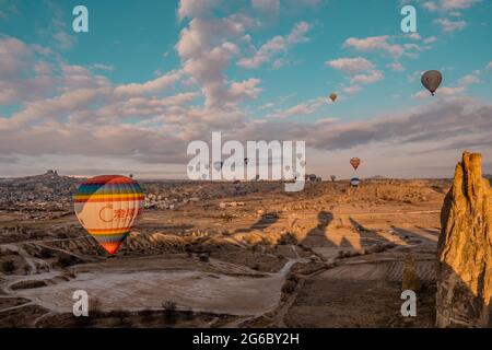 Göreme, Türkei - 19. März 2021 - herrlicher Panoramablick auf Landschaften mit Heißluftballonfahrten, die in Kappadokien, Türkei, bei Sonnenaufgang fliegen Stockfoto