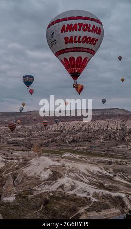 Göreme, Türkei - 19. März 2021 - herrlicher Panoramablick auf Landschaften mit Heißluftballonfahrten, die in Kappadokien, Türkei, bei Sonnenaufgang fliegen Stockfoto