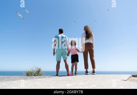 Familie von Mutter Vater und Junge, die in Zukunft Hände im Sommer halten, Rückansicht, Lebensversicherung Stockfoto