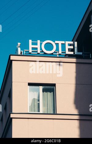Hotelschild, Wort, Ikone, geschrieben auf dem Dach eines Gebäudes, alte weiße Buchstaben, vertikal Stockfoto