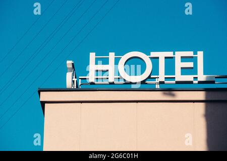 Hotelschild, Wort, Ikone, geschrieben auf einem Dach eines Gebäudes, alte weiße Buchstaben Stockfoto