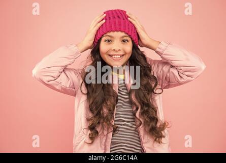 Happy girl Kind Lächeln mit Schönheit Look und lange Brünette Haar Fixierung Mode Mütze Hut auf Kopf rosa Hintergrund, Herbst Stockfoto