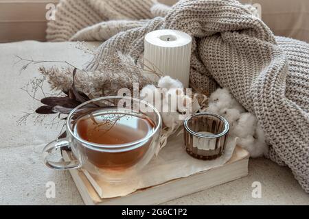 Stillleben im skandinavischen Stil mit einer Tasse Tee, einem gestrickten Element und einem Buchkopierraum. Stockfoto