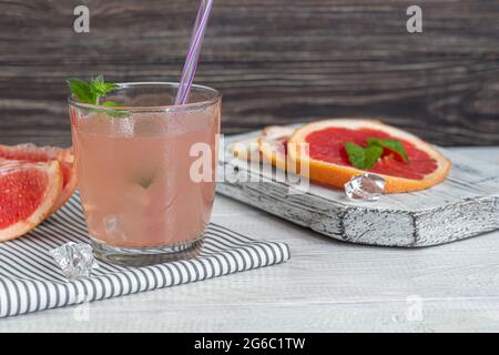 Cocktail mit Grapefruit auf hellem Hintergrund mit einem Zweig Minze und Eiswürfeln. Isolieren. Speicherplatz kopieren. Stockfoto