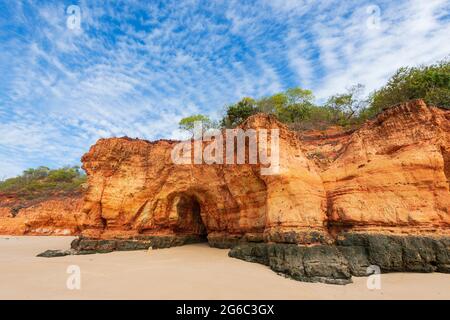 Spektakuläre Aussicht auf leuchtend rote Pindan Klippen mit einer Höhle unter einem Makrelenhimmel, Pender Bay Escape, Dampier Peninsula, Western Australia Stockfoto