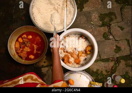 Eine Frau kocht Biryani. Biryani ist ein indo-arisches Wort, das vom persischen Wort „Birian“ abgeleitet wurde, was ‘vor dem Kochen gebraten’ und „Birinj“, das persische Wort für Reis, bedeutet. Die Biryani ist eines der beliebtesten und bestellten Gerichte in Indien. Es wird mit indischen Gewürzen, Reis und Fleisch (Huhn, Rindfleisch, Ziege, Lamm, Garnelen, Fisch), und manchmal, zusätzlich, Eier oder Gemüse wie Kartoffeln in bestimmten regionalen Sorten. Es gibt verschiedene Theorien über die Herkunft dieses leckeren Gerichts. Viele Historiker glauben, dass Biryani aus Persien stammte und von den Moguln nach Indien gebracht wurde. Stockfoto