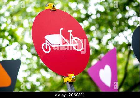 Hannover, Deutschland. Juli 2021. Ein rotes Schild mit dem Piktogramm eines Lastenfahrrads steht auf einem geschlossenen Parkplatz am Köbelinger Markt inmitten zahlreicher Schilder mit weiteren Piktogrammen. In den kommenden Wochen wird die Stadt mehrere Straßen im Stadtzentrum für den Autoverkehr schließen. Sie sollen zu temporären Fußgängerzonen werden. Quelle: Hauke-Christian Dittrich/dpa/Alamy Live News Stockfoto