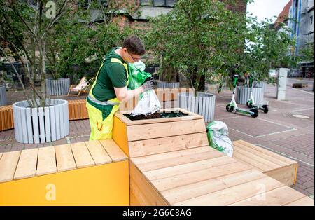 Hannover, Deutschland. Juli 2021. Ein Mitarbeiter der Stadt Hannover füllt die Blumenbeete eines temporären Sitzbereichs auf der teilweise geschlossenen Schmiedestraße in der Innenstadt mit Erde. Die Stadt schließt in den kommenden Wochen mehrere Straßen im Stadtzentrum für den Autoverkehr. Sie sollen zu temporären Fußgängerzonen werden. Quelle: Hauke-Christian Dittrich/dpa/Alamy Live News Stockfoto