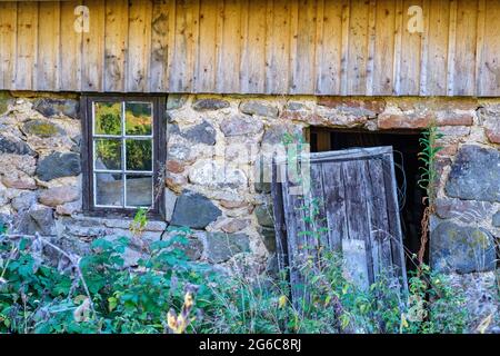 Kaputte Tür in einem verlassenen Haus mit einem überwucherten Garten Stockfoto