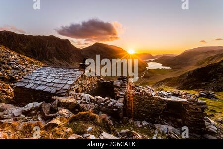 Warnscale Bothy Sonnenuntergang mit einem großen Sonnenstrahl, der über die Bergkamm-Linie hereinkommt und in Richtung Buttermere Lake blickt. Stockfoto