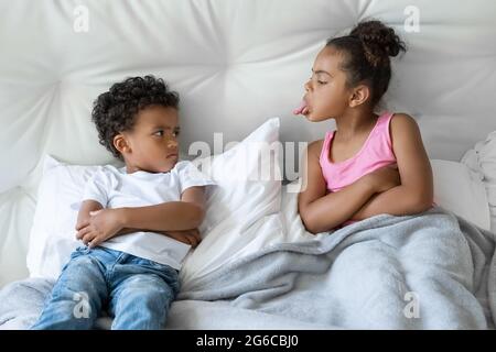 Afroamerikanische Schwester und Bruder, kleine Kinder streiten sich im Bett liegend Stockfoto