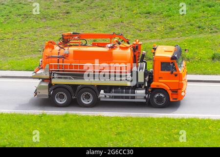 Oranger LKW mit Tank und Wasserpumpensystem fährt auf der Autobahn Stockfoto