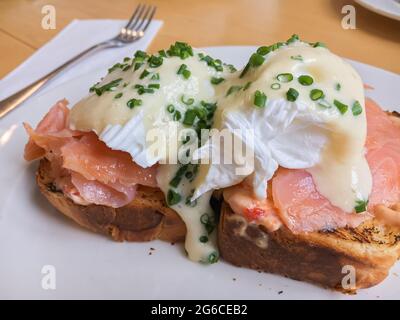 Köstliches Frühstück oder Brunch, Egg benedict mit geräuchertem Lachs und grüne Zwiebeln auf gegrilltem Toast Stockfoto