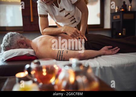 Grizzled tätowierte männliche während der Heilung Rückenmassage Stockfoto