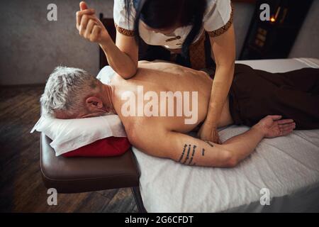 Weibliche asiatische Masseur Heilung tattoed männlichen Rücken Stockfoto