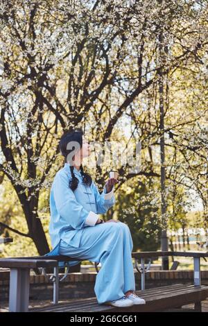 Dame in Kung Fu Uniform genießt die Natur beim Tee trinken Stockfoto