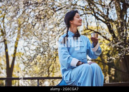 Zufriedener Kampfkünstler, der eine Pause mit Tee in der Natur hat Stockfoto