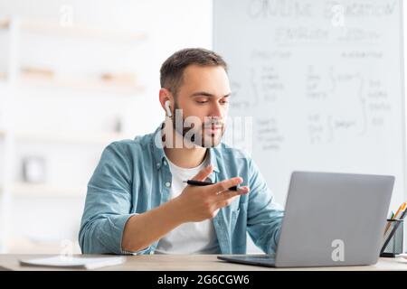 Englisch lernen online. Fokussierter männlicher Lehrer, der Fremdsprachenunterricht im Internet mit einem Laptop gibt Stockfoto