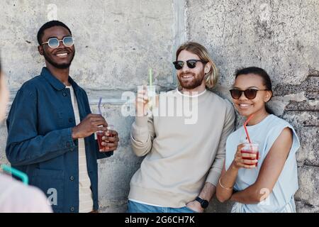 Vielfältige Gruppe von fröhlichen jungen Menschen, die Cocktails im Freien in einer städtischen Umgebung genießen, Copy Space Stockfoto