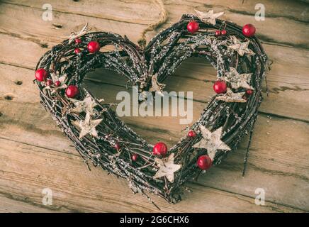 Herz aus Zweigen, verziert mit Sternen, Beeren und Glitzer als Weihnachtsdekoration Stockfoto