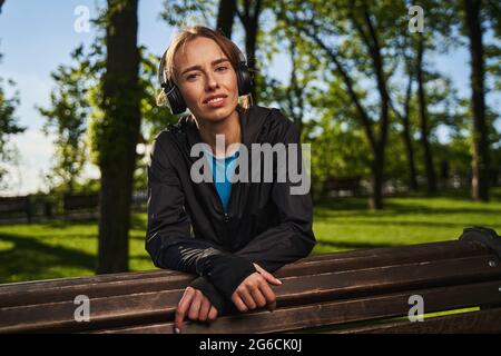 Jolly Frau entspannt im Park mit Kopfhörern Stockfoto