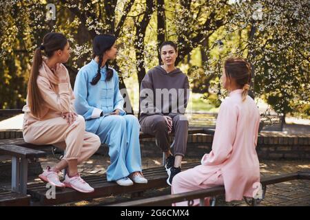 Seriöse Frau, die im Freien aufmerksamen Freunden eine Geschichte erzählt Stockfoto