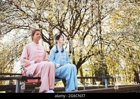 Friedliche Frauen in Kung Fu-Uniformen meditieren unter freiem Himmel Stockfoto