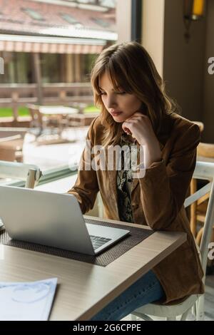Hübsche Frau, die im Café einen Laptop benutzt Stockfoto