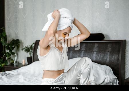 Selbstpflege, Schönheit, Hautroutine, tägliche Hautpflege und Wellness. Junge Frau im Schlafanzug, Handtuch auf dem Kopf und mit kosmetischen Kollagenflecken darunter Stockfoto